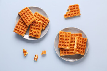 Plates with tasty Belgian waffles on blue background