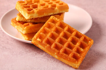 Plate with tasty Belgian waffles on pink background