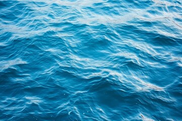 Top view of blue ocean water with intricate wave textures and water splashes, creating an abstract background of the sea surface, showcasing the dynamic movement and vibrant blue tones of the ocean.