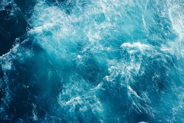 Obraz premium Top view of blue ocean water with intricate wave textures and water splashes, creating an abstract background of the sea surface, showcasing the dynamic movement and vibrant blue tones of the ocean.