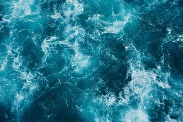 Obraz premium Top view of blue ocean water with intricate wave textures and water splashes, creating an abstract background of the sea surface, showcasing the dynamic movement and vibrant blue tones of the ocean.