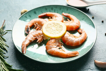 Plate with tasty boiled shrimps, rosemary and lemon on green background