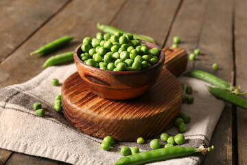 Bowl of green peas on wooden background
