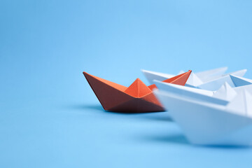 orange paper ship leading white paper ships, for leadership concept.