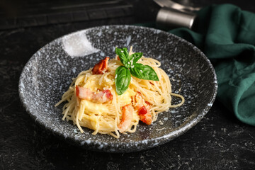 Bowl with tasty pasta carbonara on dark background, closeup