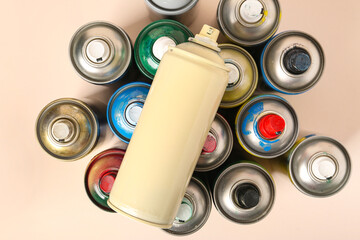 Many spray paint cans on beige background
