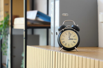 Black alarm clock on commode in office, closeup