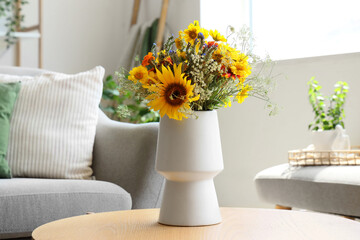 Vase with wild flowers on coffee table in interior of living room. Closeup