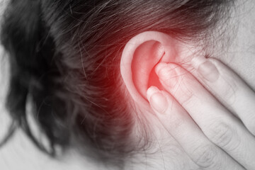 close up of a person with a earache, holding their ear, painful area highlighted in red, tinnitus problem, health problems, hearing problems or hearing loss concept.