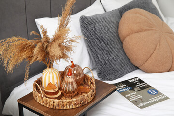 Vase with pampas grass and decorative pumpkins on table in bedroom, closeup