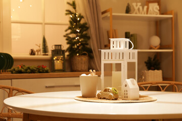 Cup of cocoa with lantern and Christmas decor on dining table in dark kitchen, closeup