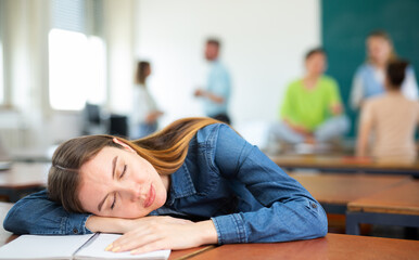 Tired young woman fell asleep at a lecture in a university auditorium
