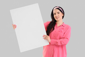 Young woman with pink ribbon and blank poster on light background. Breast cancer awareness concept