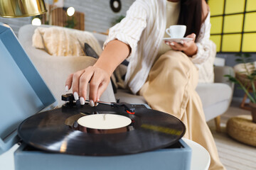 Young woman with coffee cup and record player at home, closeup