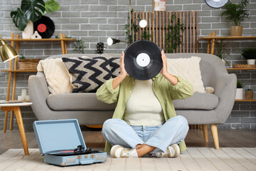 Young woman with vinyl disk for record player at home
