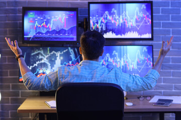 Male trader working in office at night, back view