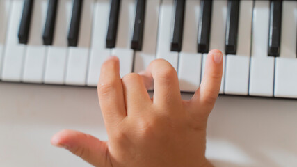 close-up of a child's hands playing the keys of a piano synthesizer