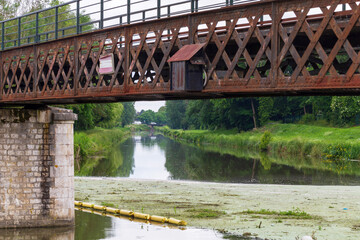 Obraz premium Rustic iron bridge spanning the tranquil intersection of Canal d'Orléans and Canal de Briare in the scenic French countryside
