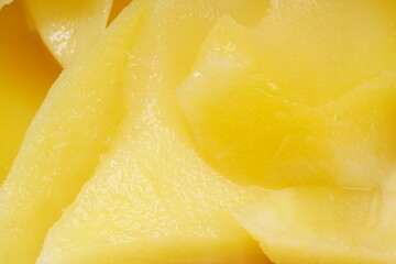 Young mango kickshaw, made from thinly sliced tangy yellow mango, placed on a wooden dish, photographed with a white background.