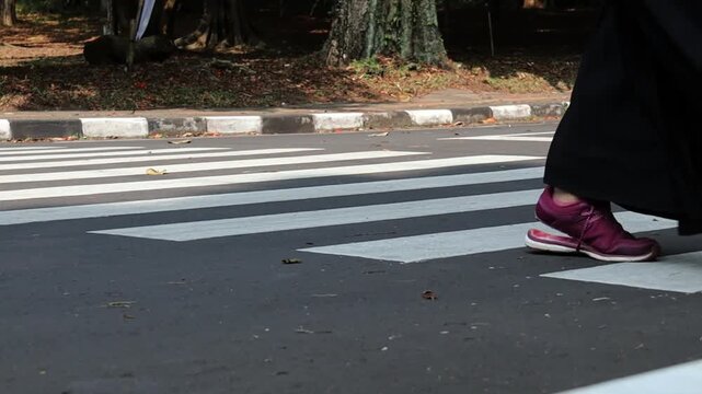 A pedestrian uses a zebra crossing to safely cross the road. This video captures the importance of pedestrian safety in urban environments. Ideal for traffic safety and city life themes