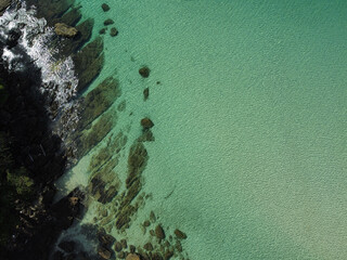 Aerial view of rocky beach in Koh Kood with turquoise calm water and the reflection of the sun; high angle view of tropical island, Trat, Thailand