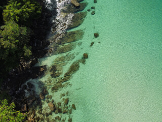 Aerial view of rocky beach in Koh Kood with calm turquoise water, drone view of the tropical island in Trat, Thailand
