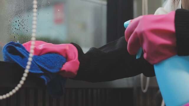 glass cleaner on a sheet of Cleaning glass window with a cloth special rag blue. close up hand