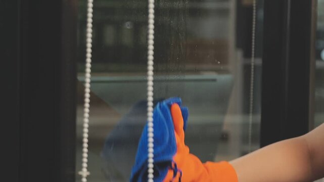 glass cleaner on a sheet of Cleaning glass window with a cloth special rag blue. close up hand