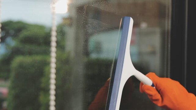 glass cleaner on a sheet of Cleaning glass window with a cloth special rag blue. close up hand