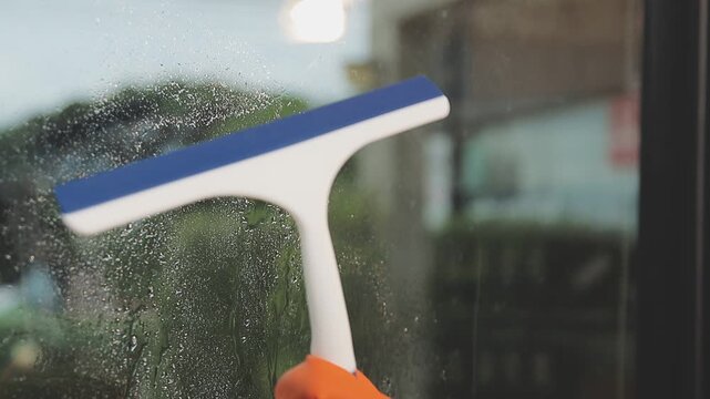 glass cleaner on a sheet of Cleaning glass window with a cloth special rag blue. close up hand