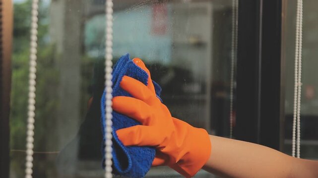 glass cleaner on a sheet of Cleaning glass window with a cloth special rag blue. close up hand