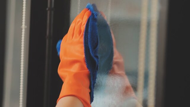 glass cleaner on a sheet of Cleaning glass window with a cloth special rag blue. close up hand