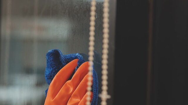 glass cleaner on a sheet of Cleaning glass window with a cloth special rag blue. close up hand