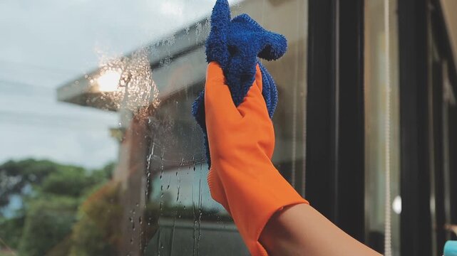 glass cleaner on a sheet of Cleaning glass window with a cloth special rag blue. close up hand