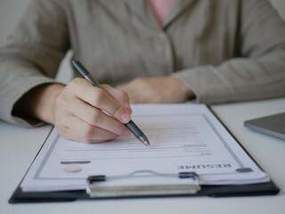 Business woman employer holds resume and talks with job applicant for job interview about her career and personal history in company, recruitment concept