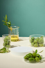 Minimalist advertising concept featuring fresh olives, branches, and oil on lab glassware, with white platform in middle, showcases products.