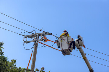 Working on high voltage power line, an electrician officer uses insulated basket to maintain service
