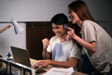Asian young man overworking at home at night in bedroom with his wife. 
