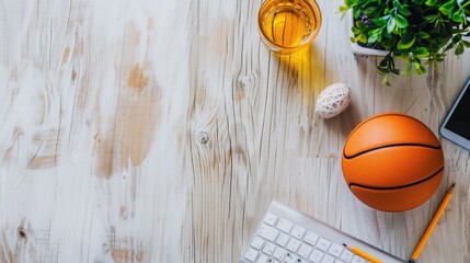 Workstation essentials basketball ball, laptop, keyboard, phone, plant on wooden table with copy space