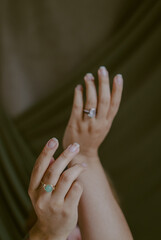 woman hands moving dancing movement without nail paint wearing rings on textile green background 