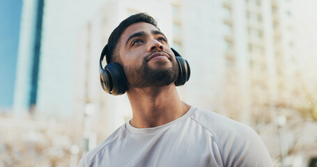 Sports, headphones and man in city for running, workout or training for race endurance or stamina. Thinking, fitness and male athlete with audio tech for podcast, music or radio with cardio exercise.