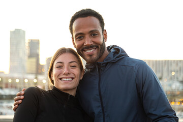 Fototapeta premium Young multiracial couple looking at camera smiling after workout outdoors during sunset.