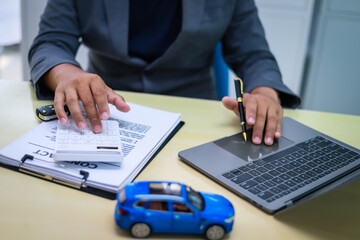 A businessman is working at his desk, focused on car financing, car sales, and insurance. He is analyzing customer data related to automobile financing and crafting strategies to improve sales