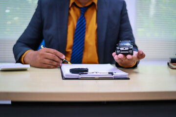 Fototapeta premium A businessman is working at his desk, focused on car financing, car sales, and insurance. He is analyzing customer data related to automobile financing and crafting strategies to improve sales