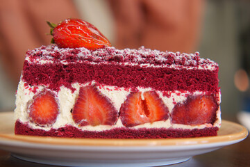 A delicious slice of Red Velvet Strawberry Cake topped with rich cream and delightful frosting