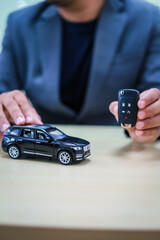 A businessman is working at his desk, focused on car financing, car sales, and insurance. He is analyzing customer data related to automobile financing and crafting strategies to improve sales