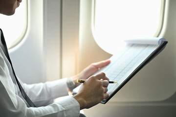 Close up image of pilot reviewing flight plans or other important information while sitting in an...