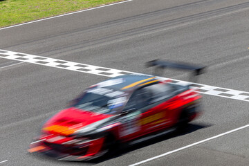 Motion blur race car racing on speed track, Car race on the international circuit race track crossing start and finish line, Race car crossing start and finish line, Target business achieve victory.