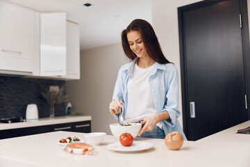Woman preparing healthy meal in the kitchen with fresh vegetables and a plate of delicious food