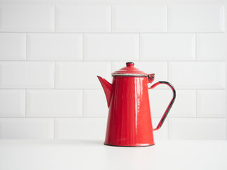 old fashion red enameled steel coffee pot isolated on table with white tile backgrounds and copy space. Concept of kitchen utensils and coffee